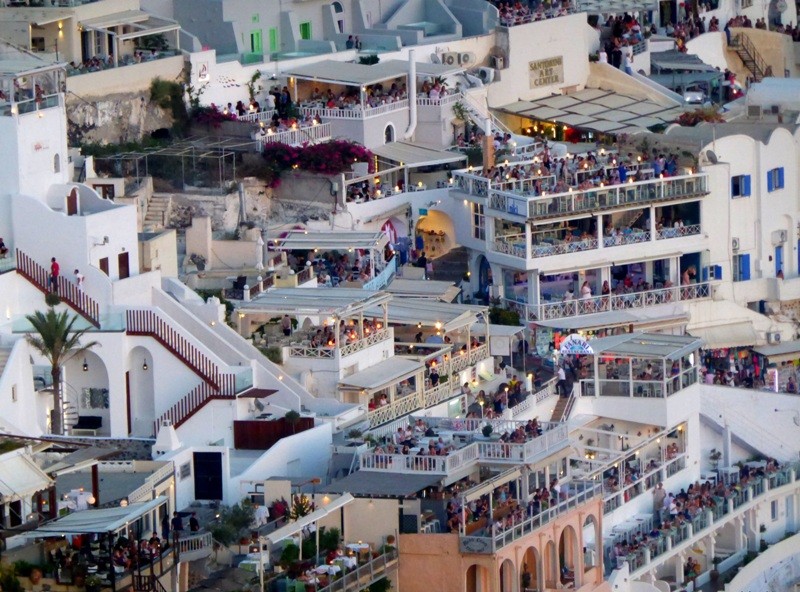 Varandas e restaurantes em Firá em Santorini, com a multidão de turistas esperando o pôr do sol