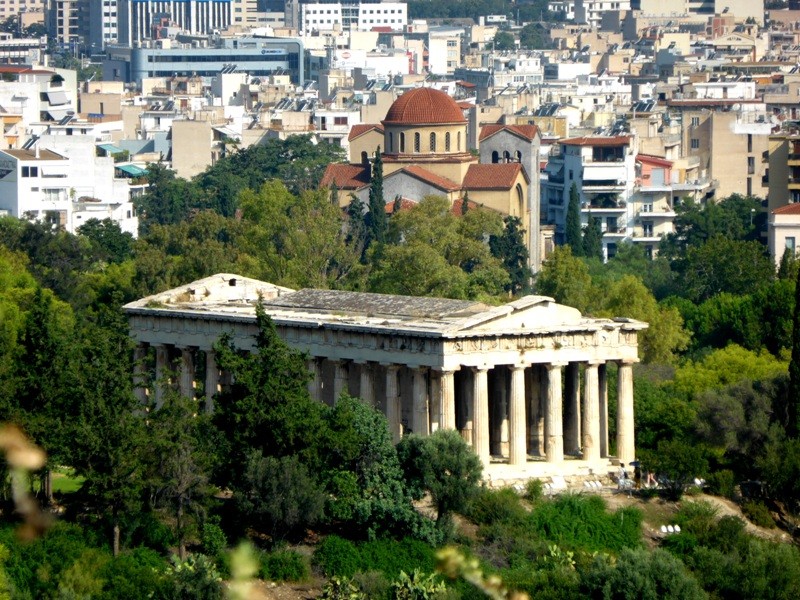 A arquitetura clássica do Templo de Hefesto contrastando com a atualidade de Atenas 